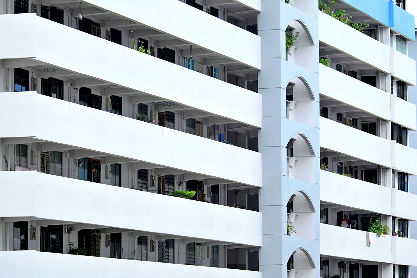 Nowoczesny budynek mieszkalny z białymi balkonami i łukowymi detalami architektonicznymi.